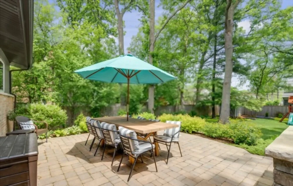 Paver patio with table, chairs, and umbrella next to green lawn in Owasa